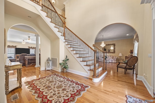 entrance foyer with arched walkways, visible vents, and hardwood / wood-style flooring