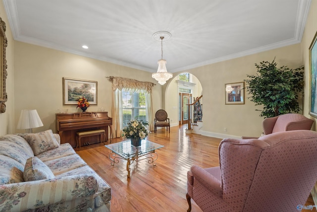 living room featuring baseboards, stairway, ornamental molding, light wood-style floors, and a notable chandelier