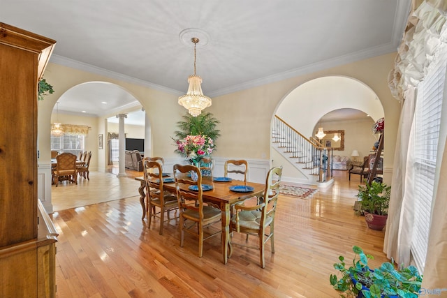 dining area with arched walkways, light wood finished floors, and a wealth of natural light