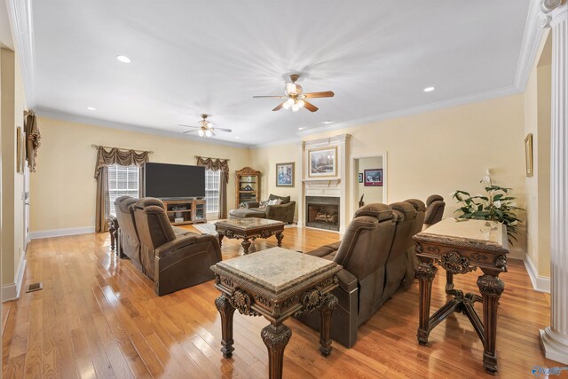 living area with light wood-style floors, crown molding, a fireplace, and baseboards