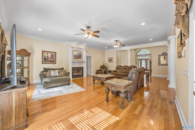 living room with a fireplace, visible vents, baseboards, light wood-style floors, and ornate columns