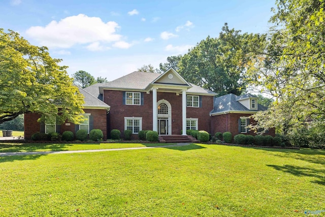 neoclassical / greek revival house with brick siding and a front lawn