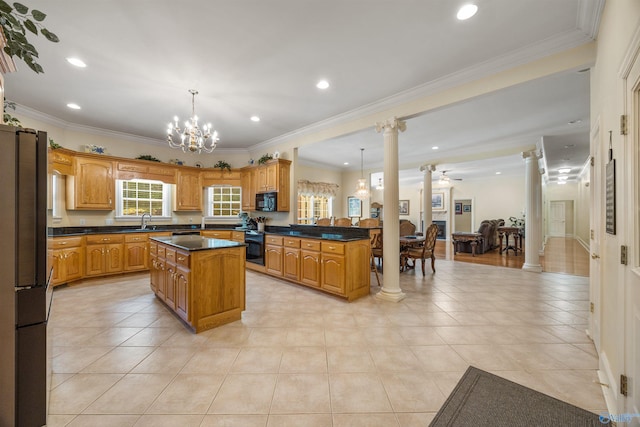 kitchen with dark countertops, ornate columns, a sink, and hanging light fixtures