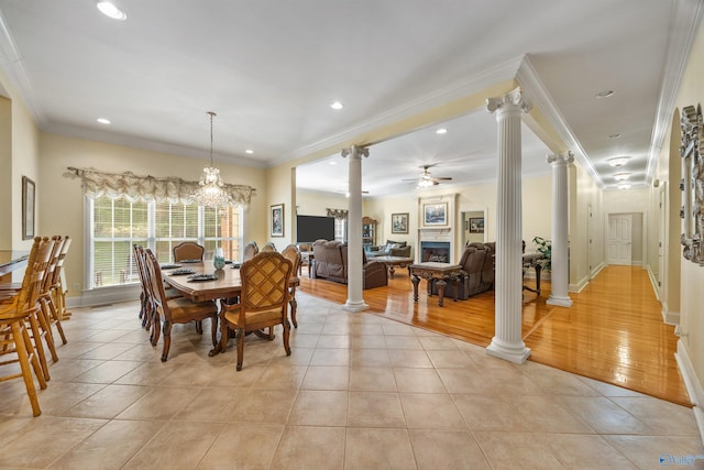 dining area featuring crown molding, a fireplace, decorative columns, and light tile patterned floors