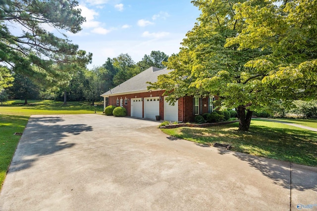 view of side of property with brick siding, driveway, an attached garage, and a lawn