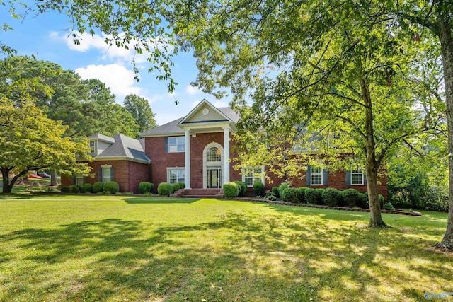 neoclassical home featuring brick siding and a front lawn