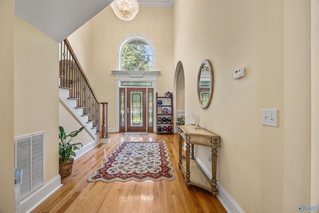 foyer entrance with visible vents, stairway, a high ceiling, baseboards, and hardwood / wood-style flooring