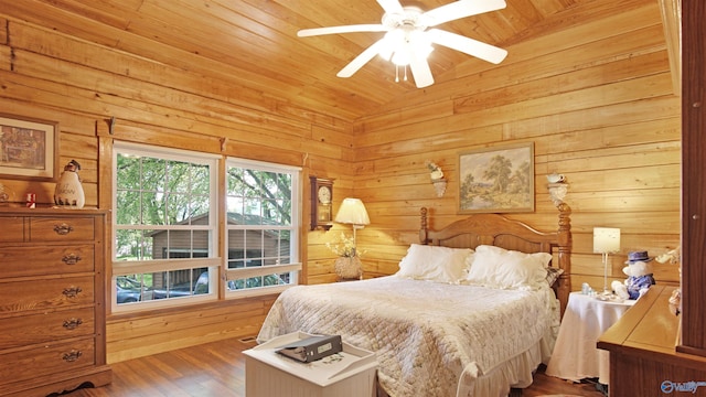 bedroom featuring ceiling fan, wood-type flooring, wood ceiling, wooden walls, and vaulted ceiling