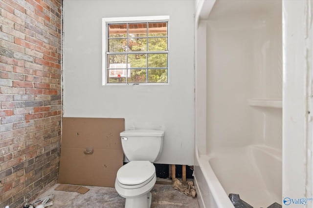 bathroom featuring tile patterned flooring, brick wall, and toilet