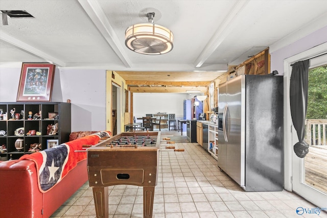 kitchen featuring beamed ceiling, stainless steel fridge, and light tile patterned floors