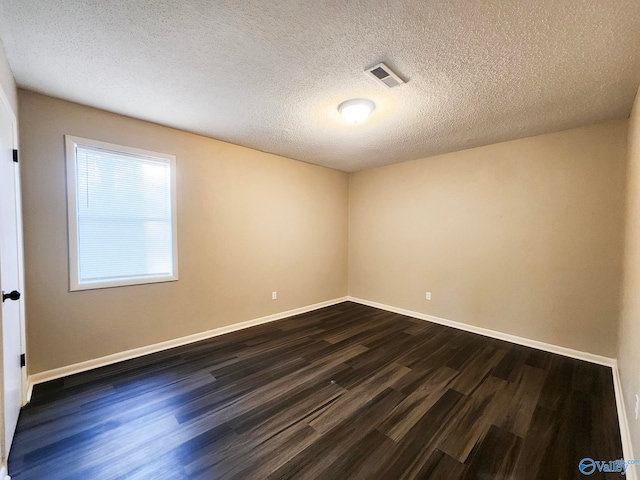 unfurnished room with dark wood-type flooring, visible vents, baseboards, and a textured ceiling