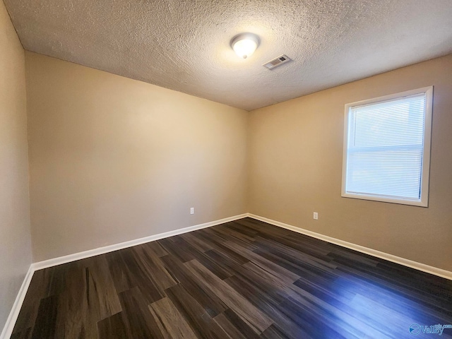 empty room with visible vents, baseboards, a textured ceiling, and dark wood-style flooring