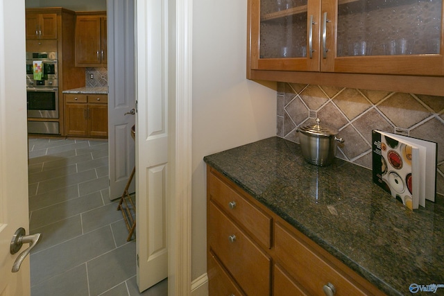 bar with tasteful backsplash, stainless steel double oven, a warming drawer, and tile patterned floors