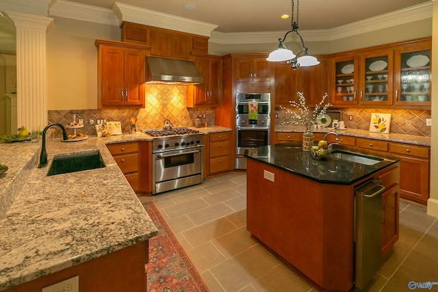 kitchen featuring light tile patterned flooring, tasteful backsplash, wall chimney range hood, an island with sink, and sink