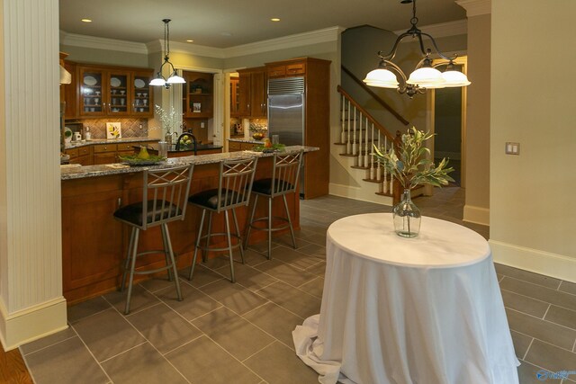 bar featuring stairway, decorative light fixtures, stainless steel built in refrigerator, crown molding, and backsplash