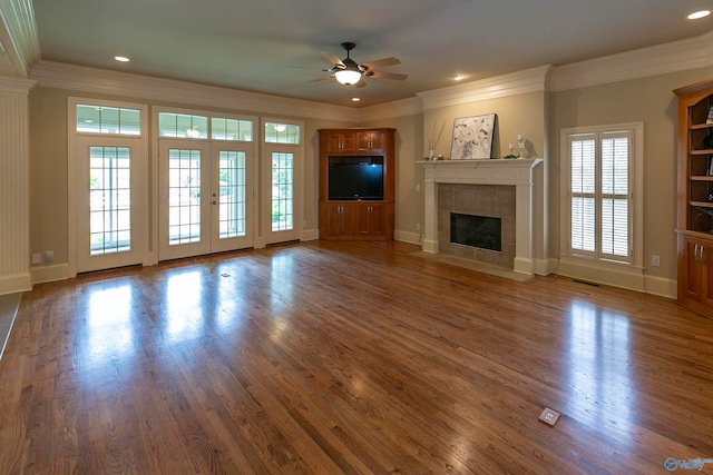 unfurnished living room with a tile fireplace, ceiling fan, hardwood / wood-style flooring, and ornamental molding