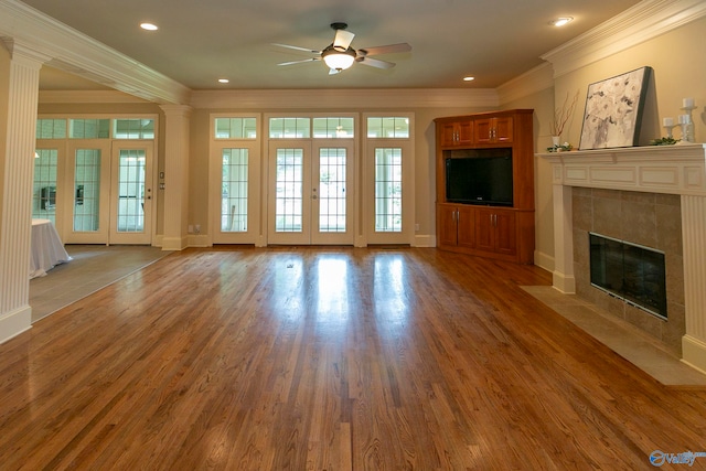 unfurnished living room with hardwood / wood-style floors, a fireplace, french doors, crown molding, and ceiling fan