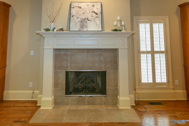 interior details featuring decorative columns, a tiled fireplace, and hardwood / wood-style floors