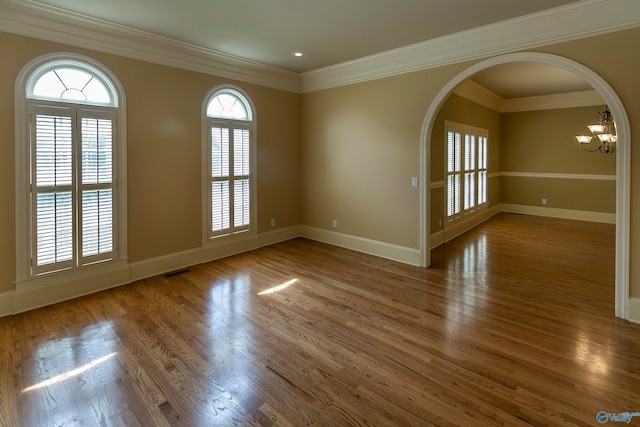 spare room featuring hardwood / wood-style flooring, a chandelier, and ornamental molding