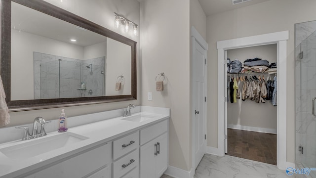 bathroom featuring a stall shower, marble finish floor, and a sink