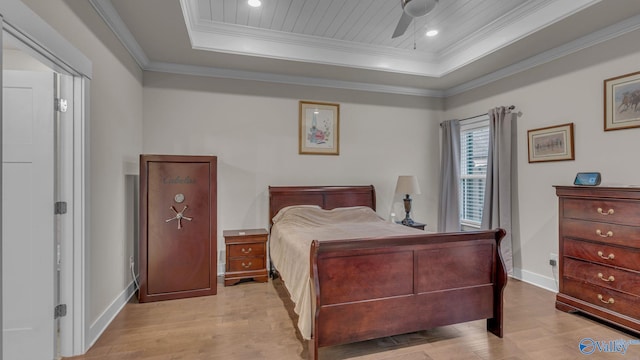 bedroom featuring crown molding, baseboards, wood finished floors, and a tray ceiling