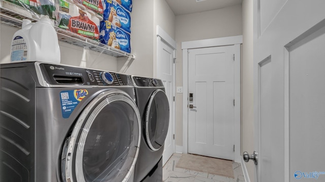 laundry area featuring baseboards, marble finish floor, laundry area, and washing machine and dryer