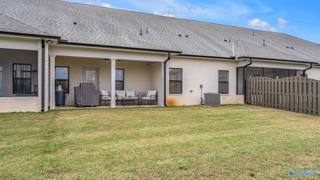 rear view of property with a patio area, an outdoor living space, a yard, roof with shingles, and fence
