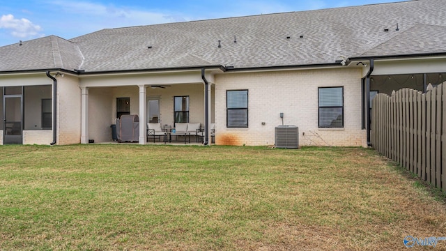 rear view of house with a patio, a shingled roof, a lawn, and central air condition unit
