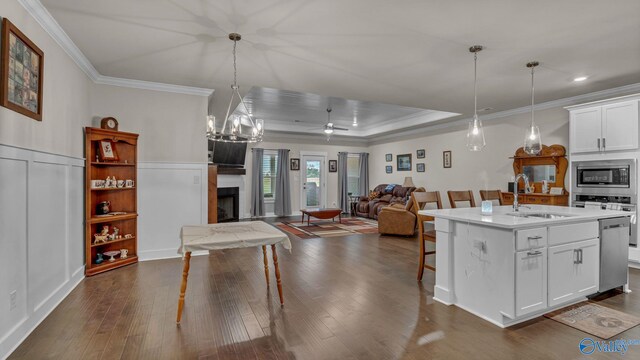 kitchen featuring a kitchen breakfast bar, a sink, stainless steel appliances, ornamental molding, and a fireplace
