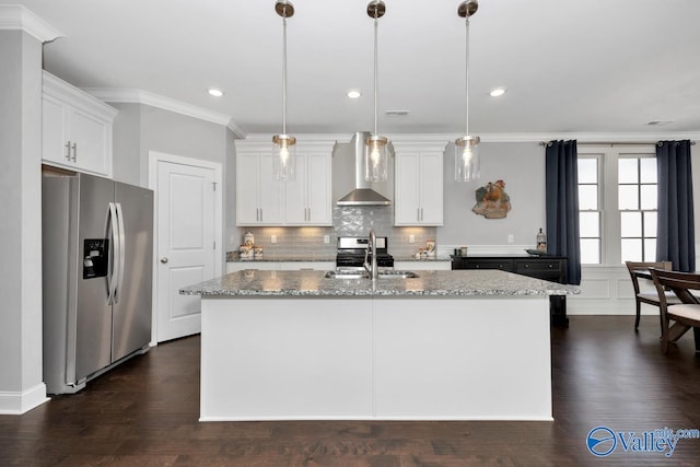 kitchen with stainless steel appliances, wall chimney range hood, light stone counters, pendant lighting, and a center island with sink