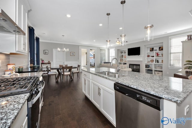 kitchen with wall chimney exhaust hood, a kitchen island with sink, white cabinets, and appliances with stainless steel finishes