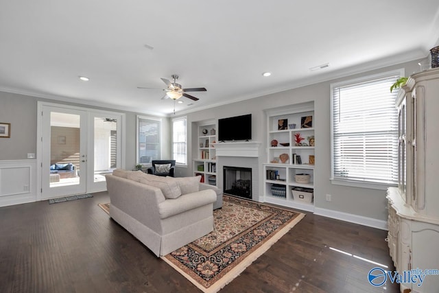 living room with built in shelves, ceiling fan, a healthy amount of sunlight, and ornamental molding