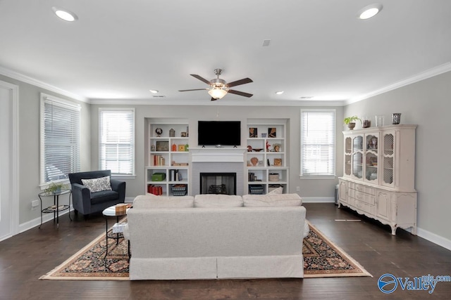 living room with built in shelves, a brick fireplace, ceiling fan, and ornamental molding