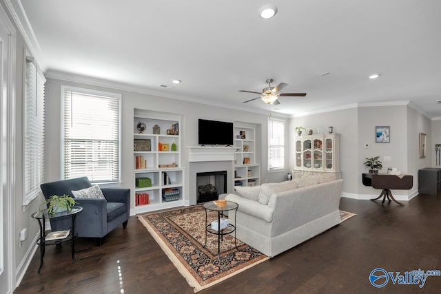 living room featuring built in shelves, ceiling fan, dark hardwood / wood-style floors, a fireplace, and ornamental molding