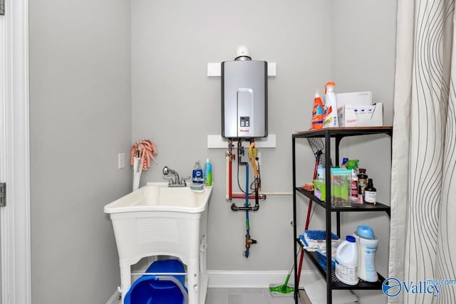 clothes washing area with tankless water heater and sink