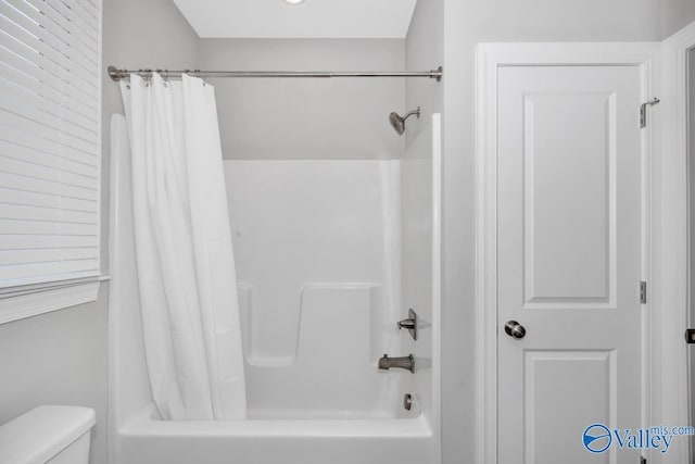 bathroom featuring shower / bath combo with shower curtain and toilet