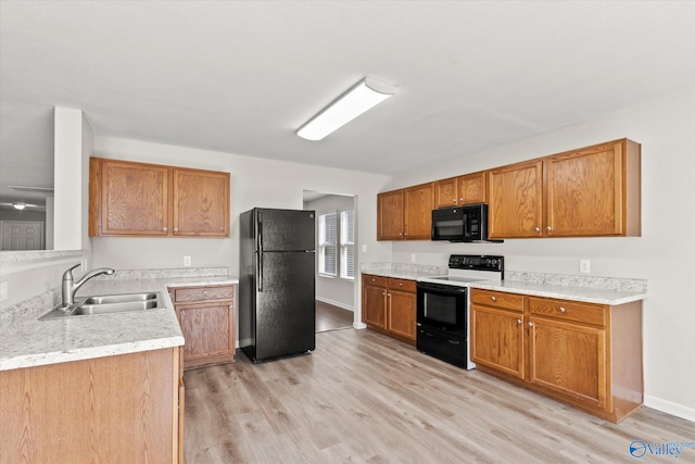 kitchen featuring sink, black appliances, and light hardwood / wood-style flooring