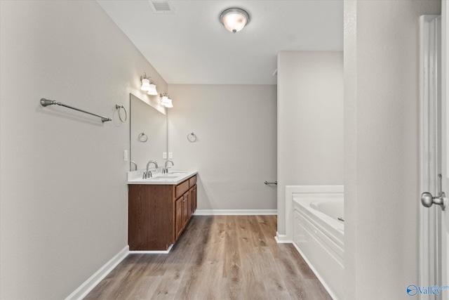 bathroom featuring hardwood / wood-style floors, vanity, and a tub to relax in