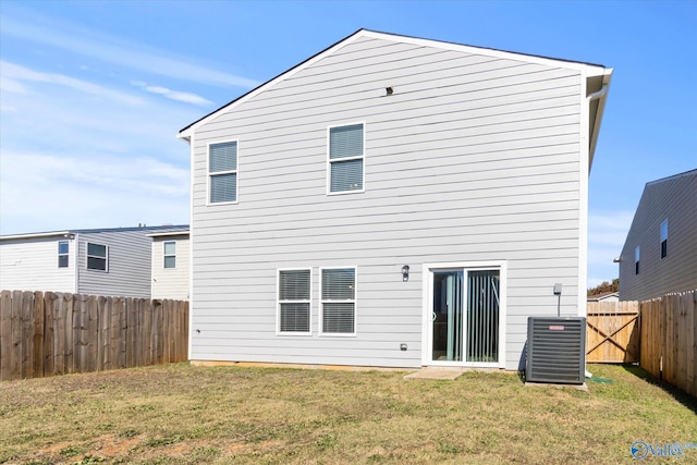 rear view of house with central AC and a yard