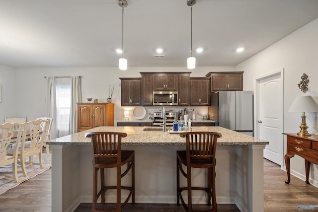165 Saddle St, New Market, AL 35761 - kitchen featuring appliances with stainless steel finishes, dark brown cabinets, a kitchen island with sink, dark wood-style floors, and a breakfast bar area