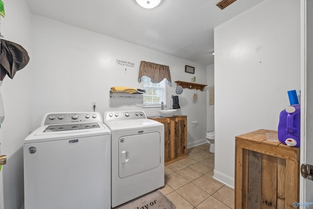 laundry area with washing machine and clothes dryer, light tile patterned flooring, and sink