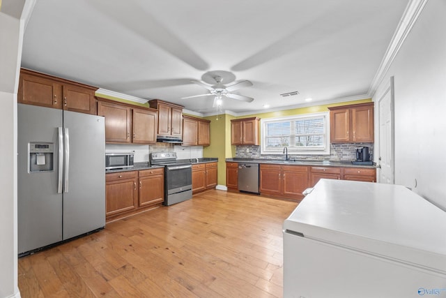 kitchen with light hardwood / wood-style flooring, sink, ornamental molding, and stainless steel appliances