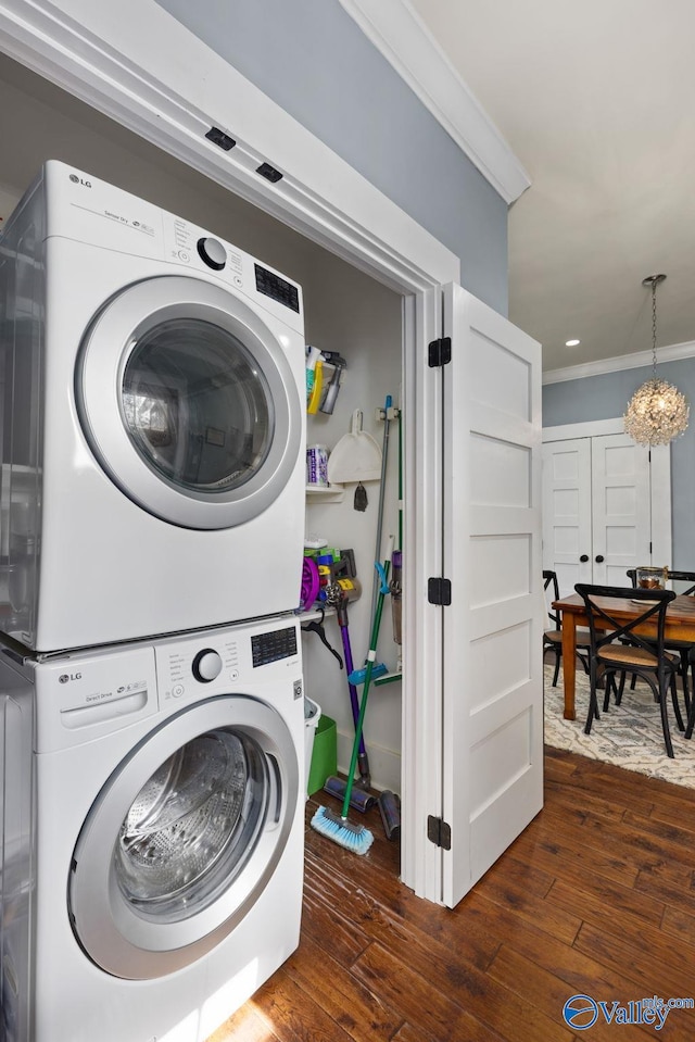 washroom with stacked washer / drying machine, a notable chandelier, ornamental molding, and dark hardwood / wood-style floors