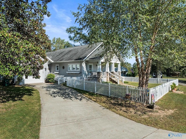 view of front of home featuring covered porch, a garage, and a front lawn