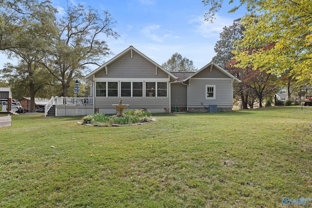 rear view of house featuring a wooden deck and a lawn