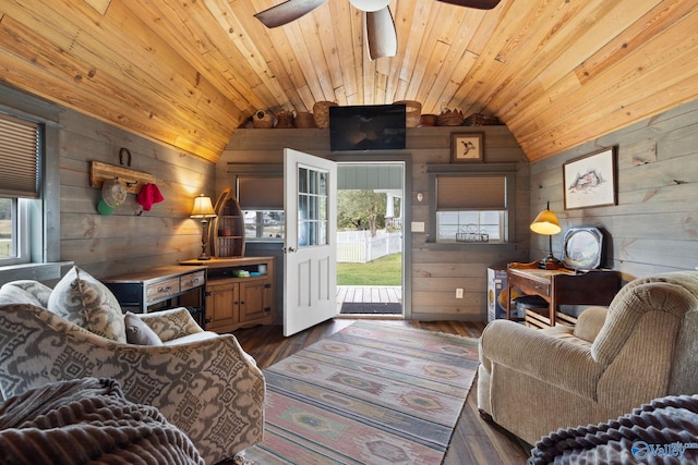 living room with hardwood / wood-style floors, lofted ceiling, wooden walls, and a healthy amount of sunlight