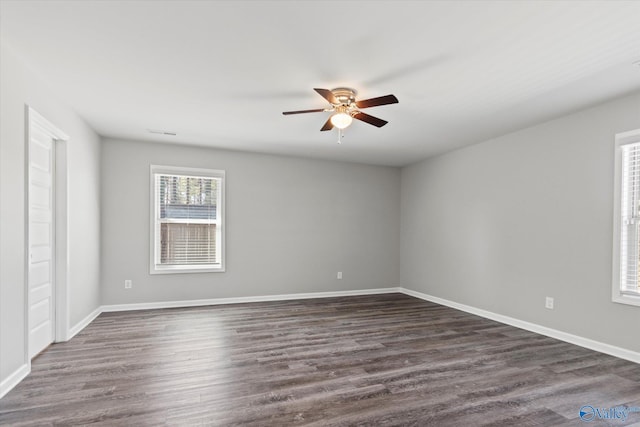 empty room with dark wood-style floors, ceiling fan, and baseboards