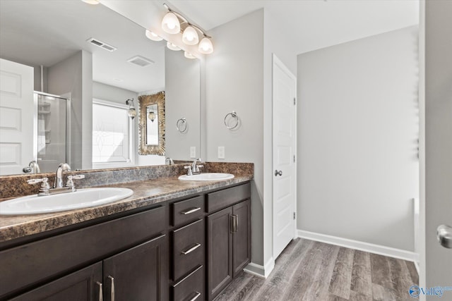 full bathroom featuring a stall shower, visible vents, a sink, and wood finished floors