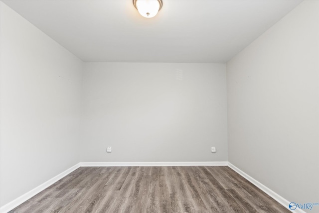 spare room with baseboards and wood finished floors