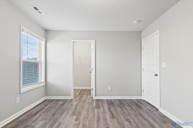 empty room featuring wood finished floors, visible vents, and baseboards